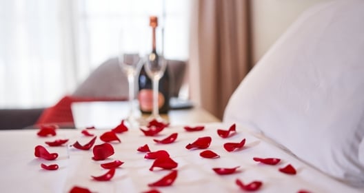 Bed with white bedclothes covered with rose petals