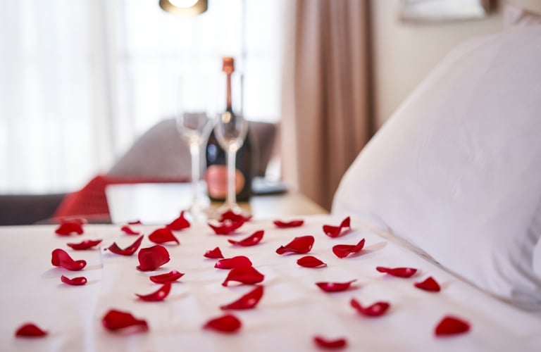 Bed with white bedclothes covered with rose petals